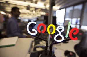 A neon Google logo is seen as employees work at the new Google office in Toronto