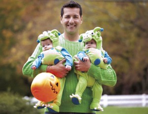 Hispanic father holding twin babies in Halloween costumes